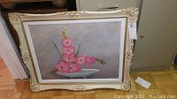 Full view of framed floral art print depicting pink gladiolus flowers in a white bowl with gray background.