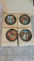 Four Bradford Exchange collectible plates with original boxes placed on tile floor showing colorful classical figure scenes.