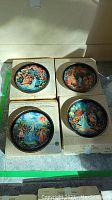 Four decorative collectible plates from Bradford Exchange's Snowmaiden Series laid on original boxes showing detailed scenes from folklore