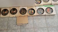 Six Bradford Exchange Russian Series collectible plates displayed on floor, each plate in original box, showing colorful Russian folklore scenes with black background and gold borders.