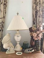 Wide view showing marble lamp, pottery sculpture, resin duck, figurines, vase, and trinket jar on wooden surface