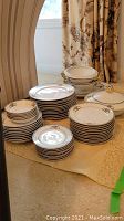 Multiple stacks of round plates and bowls with serving pieces arranged on floor