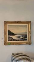 Full view of the oil painting depicting coastal landscape, framed in ornate frame with some damage visible.