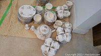 Full view of stacked cups, saucers, plates, bowls with teapot, creamer, sugar and shakers