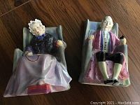 Both Joan and Darby figurines on wooden surface, front view