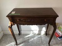 Front view of the wood side table showing carved drawer front and cabriole legs.
