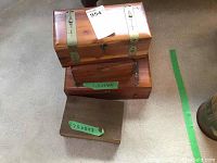 Four wooden boxes stacked or grouped, showing different textures and metal accents, with size labels visible on two boxes.