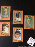 Front view of five baseball cards laid out on black background, showing Ty Cobb, Jackie Robinson, Cy Young, Lou Gehrig, and Babe Ruth.