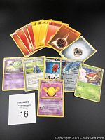 Grouped view of 14 Pokémon trading cards spread on black surface showing various types including energy, trainer, and Pokémon cards.