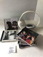 Photo showing multiple CDs stacked in front of a white Panasonic over-ear headphone set