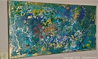 Front view of the large rectangular abstract oil painting displaying swirling mix of blue, green, gold, and other colors