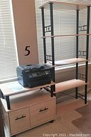 EPSON WF-2660 black all-in-one printer sitting on light wood printer table, printer table has shelf and two-door storage below.