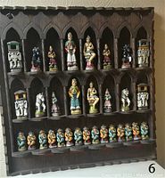 Front view of carved wooden display board with hand-painted clay chess pieces arranged in three rows of Gothic arches