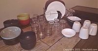 Photo showing entire assortment including ceramic bowls and plates, clear glasses, white coffee mugs, and metal dish rack.