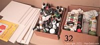 Photo showing set of white stretched canvases, palette paper, and boxes of assorted painting oils and supplies
