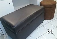 One rectangular ottoman with dark leather-like finish and one round ottoman with brown felt finish shown side by side on a tiled floor.