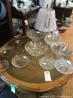 Photo of clear glass bowls and plates on a wooden table, showing variety of sizes and styles.