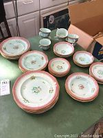 Top view of entire dish set arranged on table, showing plates, bowls, cups, and saucers with floral Lowestoff pattern and pink/gold rims