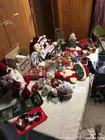 Wide shot of table filled with various Christmas ornaments and decorations, including fabric figurines, stockings, and small decor items