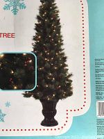 Photo showing packaging illustration of the 6.5-foot tall pre-lit artificial Christmas tree with lights and urn base.