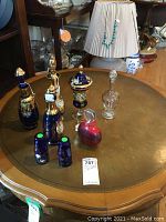 View of all glass decanters and shot glasses on round table showing hand painted details and variety of styles