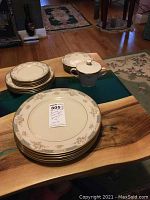 Full view of partial Lenox china set arranged on a wooden table including stacked plates and a sugar bowl with lid, all in Somerset floral pattern.