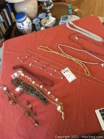 Collection of long costume necklaces arranged on an orange cloth with various styles visible