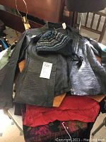 Mixed lot spread with black faux leather jacket, knit hat on top, and red and black tops beneath.