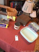Full lot with tins, Tupperware, boxes, and Longaberger basket on orange tablecloth showing all included items and context.