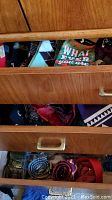 Bottom drawer containing rolled ties or suspenders, metal belt buckles, and some bow ties