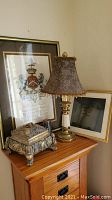 Photo of the overall arrangement showing the crest print, lamp, decorative box, and candle on a wooden dresser