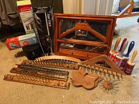 Various wooden closet organization tools laid out on floor, including hangers, racks, brushes, rollers and comb-like tools.