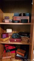 Full view of top three shelves showing mixed leather, wood, ceramic and metal boxes