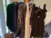 Photo showing multiple women's nightgowns and robes of different colors and styles hung on hangers.