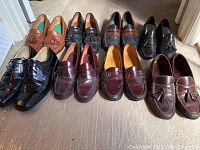Full view of nine pairs of men's dress shoes, styles include loafers and lace-up, colors range from black, brown to burgundy