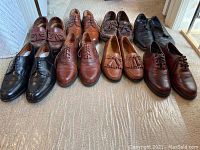 Overview of 7 pairs of men's shoes, size 9.5, arranged on floor showing style variety and condition.