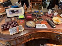 Wide view of office desk showing various office accessories including wooden abacus, framed print, pens, coins, and knives.