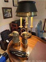 Full view of all items on a round wooden table including the lamp, eagle bookends, and telescope with case.