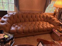 Front view of full sofa showing three-seat tufted leather design and rolled arms