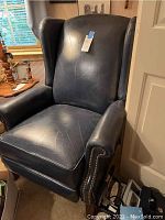 Front view of navy blue leather wingback-style recliner showing seat, back, arms and nailhead trim