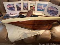 Wooden model sailboat with canvas sails and nautical themed framed photos