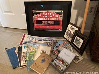 Framed photo of Wrigley Field scoreboard with Cubs win message and assorted vintage printed memorabilia including DePaul University alumni pennant