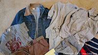 Photo showing vintage Levi denim jacket with corduroy collar, gray Texas t-shirt, brown khaki shorts, yellow shorts, and other casual clothing items on carpet.