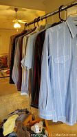 Multiple vintage Wrangler shirts and one jacket hanging on a clothing rack, various colors and patterns visible, mostly long sleeves.