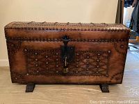 Full-frontal view of trunk showing carved panels, stud detailing, feet, lock and overall condition