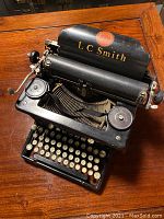 Top and front view showing 'L.C. Smith' name, keys, and carriage return lever.
