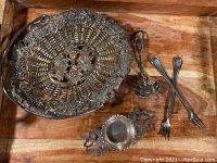 Group of five silver plated antique decorative items on wooden surface including basket, ladle, forks, and strainer.