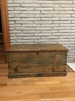 Front and side view of the antique wooden chest showing worn wood and scratches.