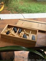 Interior of open wooden box showing six bone horse figurines and matching dark wood stands arranged in six compartments on a wood surface