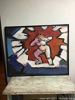 Full view of the abstract painting featuring a central figure in pink surrounded by radiating colors and bold black outlines, with a black frame.